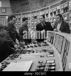 Slaviansk, Ukrainische SSR, UdSSR – 1981: Archivfoto, das den Abgeordneten Rypalenko bei einem Treffen mit Ingenieuren im Hauptkontrollraum eines Kraftwerks zeigt. Gekleidet in einem formellen Anzug mit einem Stellvertreterabzeichen hebt er sich unter den Arbeitern in Uniformen hervor. Der Hintergrund ist gefüllt mit massiven Panels mit analogen Anzeigen und Mimik-Diagrammen. Dieses Bild zeigt das Ausmaß der sowjetischen Industrieverwaltung und die technische Atmosphäre der friedlichen Donbass-Region während der späten sowjetischen Ära. Stockfoto