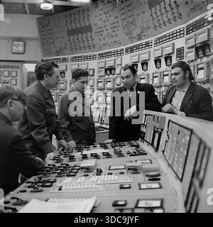 Slaviansk, Ukrainische SSR, UdSSR – 1981: Archivfoto, das den Abgeordneten Rypalenko bei einem Treffen mit Ingenieuren im Hauptkontrollraum eines Kraftwerks zeigt. Gekleidet in einem formellen Anzug mit einem Stellvertreterabzeichen hebt er sich unter den Arbeitern in Uniformen hervor. Der Hintergrund ist gefüllt mit massiven Panels mit analogen Anzeigen und Mimik-Diagrammen. Dieses Bild zeigt das Ausmaß der sowjetischen Industrieverwaltung und die technische Atmosphäre der friedlichen Donbass-Region während der späten sowjetischen Ära. Stockfoto