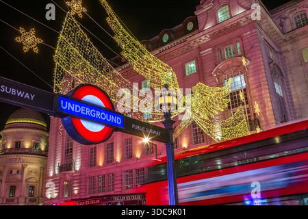 Weihnachtsdekoration, der berühmte beleuchtete Engel, roter Routemaster Bus und Piccadilly U-Bahn Schild, Regent Street, London Stockfoto