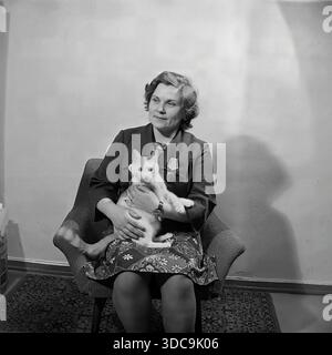 Slaviansk, Ukrainische SSR, UdSSR - 1981: Archivporträt der Stellvertreterin Ljudmila Schudinova, die mit ihrer Katze in einem Sessel sitzt. Sie trägt eine Jacke, die mit dem Orden der Ehre und anderen Auszeichnungen der Regierung verziert ist, was einen auffälligen Kontrast zwischen ihrem offiziellen Status und dem inländischen Setting schafft. Dieses Bild zeigt die persönliche Seite eines dekorierten sowjetischen Arbeiters und Politikers in der friedlichen Donbass-Region während der späten Sowjetzeit. Stockfoto