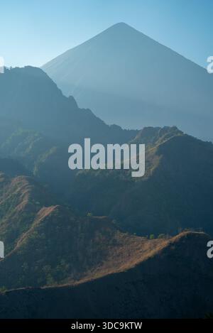 Sillhouetted Berge und Grate mit der perfekten Pyramide des Mount Inierie, einem aktiven Vulkan auf Flores Island, nahe Bajawa, Indonesien Stockfoto