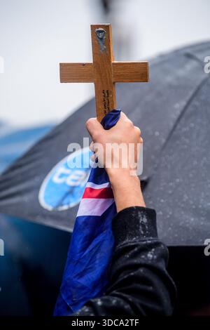 Ein Demonstrant hebt während einer Kundgebung ein hölzernes Kreuz mit einer australischen Flagge auf. Rund hundert Demonstranten versammelten sich bei starkem Regen auf den Stufen des Parlamentsgebäudes in Melbourne während einer friedlichen Kundgebung, die zur „Entlassung der Regierung“ nach dem Angriff auf Bondi aufrief. Die Demonstration umfasste Anti-Einwanderungs-Aktivisten, One Nation-Unterstützer und Organisatoren, die zuvor während Melbournes Anti-Lockdown-Proteste bekannt wurden. Die Teilnehmer zeigten australische und israelische Flaggen und beschuldigten die Staats- und Bundesregierungen politischer Misserfolge Stockfoto