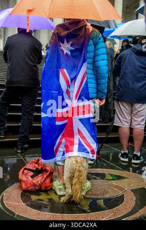 Der Hund einer Dame nimmt Schutz unter einer australischen Flagge, die von ihren Schultern hängt, während sie während einer regierungsfeindlichen Kundgebung zusieht. Rund hundert Demonstranten versammelten sich bei starkem Regen auf den Stufen des Parlamentsgebäudes in Melbourne während einer friedlichen Kundgebung, die zur „Entlassung der Regierung“ nach dem Angriff auf Bondi aufrief. Die Demonstration umfasste Anti-Einwanderungs-Aktivisten, One Nation-Unterstützer und Organisatoren, die zuvor während Melbournes Anti-Lockdown-Proteste bekannt wurden. Die Teilnehmer zeigten australische und israelische Flaggen und beschuldigten die Staats- und Bundesregierungen der Politik fa Stockfoto