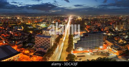 Blick auf den Sonnenuntergang über Tirana mit Blick auf Zogu i Zi und die westliche Skyline der Stadt, die von warmen Stadtlichtern erstrahlt. Stockfoto