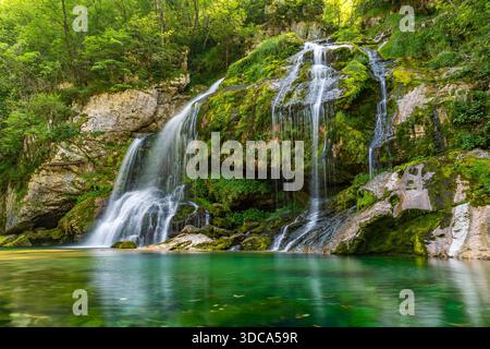 Majestätischer Wasserfall fließt anmutig in smaragdgrüner Vegetation und ruft Ruhe und Naturwunder im unberührten Soca-Tal Sloweniens hervor Stockfoto