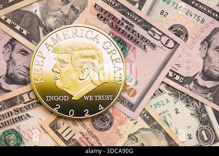 KIEW, UKRAINE - 13. DEZEMBER 2025 Trump Goldmünze auf große Menge von US-Dollar-Geldscheine Banknoten aus nächster Nähe Stockfoto