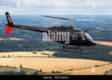 Ein Bell 206B JetRanger III Hubschrauber mit der Registrierung D-HHFW, betrieben von Heliteam, wird während des Royal International Air Tattoo in Fairford, England, in Luft-Luft-Ansicht gezeigt. Der leichte Hubschrauber zeigt einen einzelnen Hauptrotor, Heckrotor, Kufen und eine geschlossene Kabine während des koordinierten Fluges. Das Flugzeug behält eine stabile Positionierung bei und demonstriert Piloten, Aerodynamik und strukturelle Integrität. Stockfoto