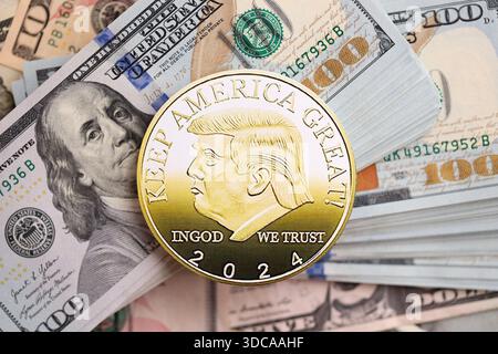 KIEW, UKRAINE - 13. DEZEMBER 2025 Trump Goldmünze auf große Menge von US-Dollar-Geldscheine Banknoten aus nächster Nähe Stockfoto