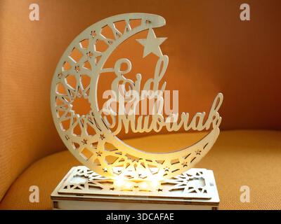 Elegantes hölzernes Eid Mubarak-Ornament mit Mondsichel und Stern mit geometrischen Mustern und warmen leuchtenden Lichtern. Stockfoto