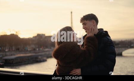 Ein romantisches Paar umarmt Paris Frankreich mit dem Eiffelturm, der bei Sonnenuntergang im Hintergrund sichtbar ist. Dieses Bild ist perfekt für die Illustration von Themen von Stockfoto