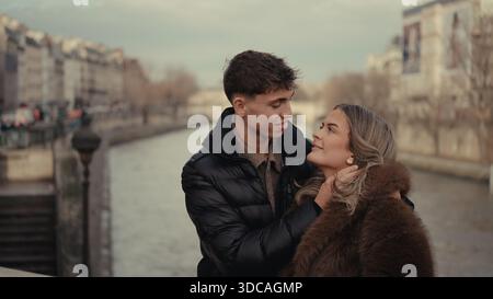 Ein romantisches Paar umarmt in Paris Frankreich mit der seine und der Stadtlandschaft im Hintergrund zeigen die jungen Liebenden Zuneigung und Zärtlichkeit Stockfoto