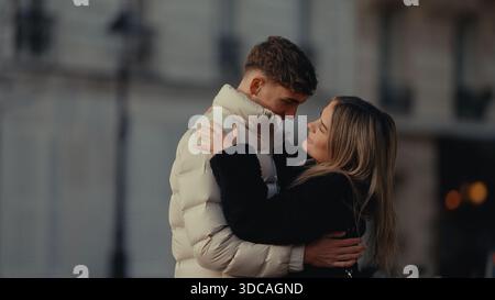 Ein romantisches junges Paar umarmt sich in Paris Frankreich und drückt Liebe und Zärtlichkeit aus. Das Paar trägt Wintermäntel und sieht sich mit Liebe an Stockfoto