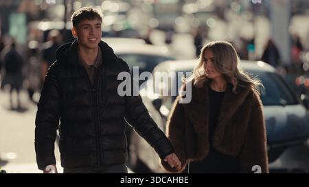 Ein junges Paar spaziert Hand in Hand durch die Straßen von Paris Frankreich der Mann und die Frau sind in stilvoller Oberbekleidung gekleidet und scheinen ein R Stockfoto