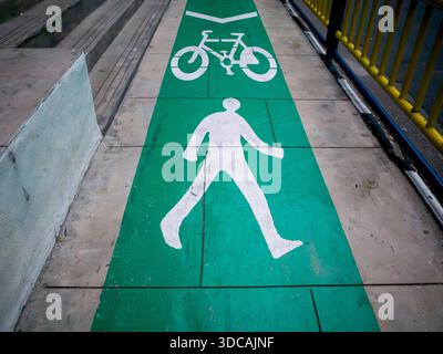Ein Symbol für Fußgänger und Fahrradwege auf einem grünen Fußweg Stockfoto