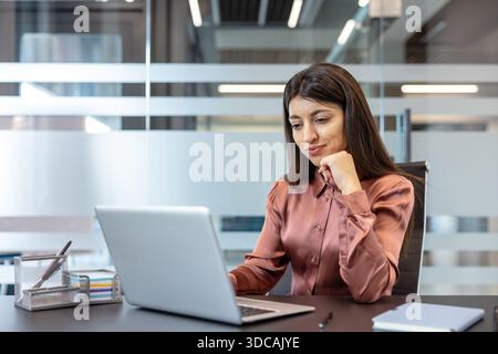 Die junge Geschäftsfrau konzentriert sich auf ihr Notebook, trifft strategische Entscheidungen und verwaltet Projekte in einem modernen Büro, wobei sie Vertrauen, Konzentration und professionelle Führung hervorbringt Stockfoto