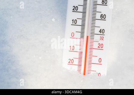 Close-up shot of outdoor thermometer with Celsius and Farenheit scale placed in a snow displays warm winter temperature Stockfoto