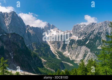 Ein atemberaubender Panoramablick auf zerklüftete Berggipfel und schneebedeckte Bergrücken im goldenen Sonnenlicht weckt Ehrfurcht und Ruhe im Triglav-Nationalpark Stockfoto