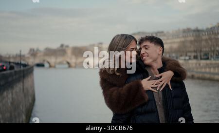 Ein romantisches Paar umarmt auf einer Brücke in Paris Frankreich mit der seine und der Stadtlandschaft im Hintergrund. Dieses Bild kann für den Reisetourismus verwendet werden Stockfoto