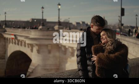 Ein romantisches Paar umarmt sich auf einer Brücke in Paris Frankreich mit einem Stadtbild im Hintergrund das Bild vermittelt Liebe und Zuneigung, die für Reisen und Reisen geeignet sind Stockfoto