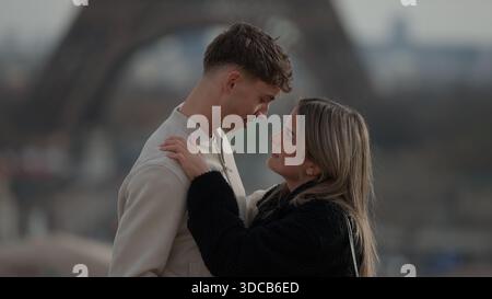 Ein romantisches Paar umarmt Paris Frankreich mit dem Eiffelturm im Hintergrund. Dieses Bild eignet sich für Reise- und Tourismusmarketing-Kampagnen Stockfoto