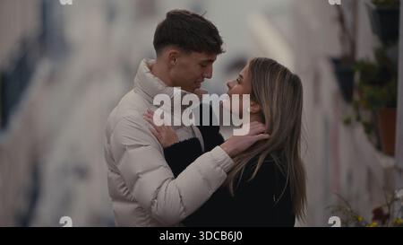 Ein romantisches Paar umarmt sich in Paris Frankreich und teilt einen Moment der Liebe und Zuneigung. Das Paar trägt Wintermäntel und der Hintergrund zeigt ein Europa Stockfoto