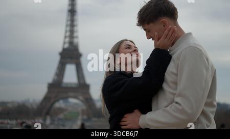 Ein romantisches Paar umarmt Paris Frankreich mit dem Eiffelturm im Hintergrund, der Liebe und Zuneigung zeigt. Dieses Bild ist perfekt für Reisen und Stockfoto