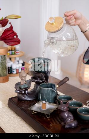 Wassergießen. Teezeremonie. Frau Hände füllen Glas Teekanne mit trinken erfrischende Flüssigkeit gesunde Lebensweise Weihrauch brennen. Stockfoto