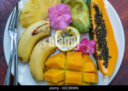 Tropische Früchte auf einem weißen Teller, Nahaufnahme. Frische Mango, Banane, Avocado, Papaya, Passionsfrucht, Ananas auf einem Teller, Sansibar, Tansania, Ostafrika Stockfoto