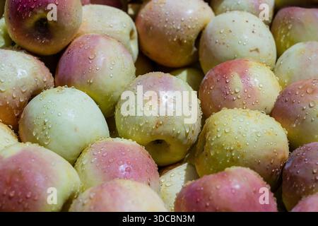 Rohe gelbe Äpfel werden auf einem lokalen Lebensmittelmarkt auf der Insel Sansibar, Tansania, Ostafrika, aus nächster Nähe verkauft. Frische Äpfel mit Wassertropfen Stockfoto