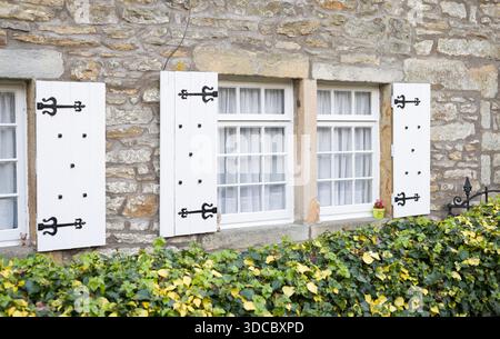 Traditionelle Holzfenster mit weißen Fensterläden auf einem alten Steinhaus in Grassington, Yorkshire Dales, Großbritannien Stockfoto