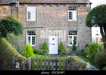 Steinhaus in Grassington, Yorkshire Dales, Großbritannien, mit Holzfenstern und Haustür und Vorgarten mit Tor Stockfoto