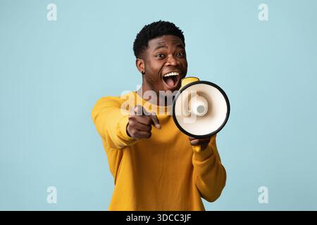 Emotionaler schwarzer Kerl mit Megaphon, der Ankündigung macht Stockfoto