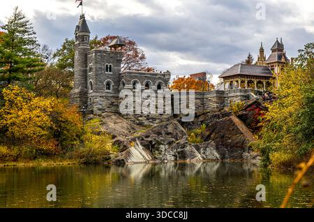 Belvedere Castle überblickt einen ruhigen Central Park See mit Steinbrücke, Wasserfall und Herbstlaub in Manhattan, New York City; perfekt für Reisen Stockfoto