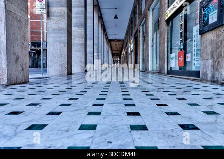 Flacher Blickwinkel entlang der historischen Porticos von Bologna, die Säulen und sich wiederholende Bögen hervorheben. Stockfoto
