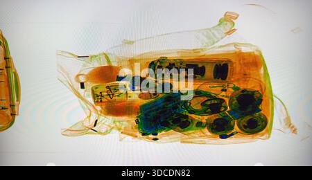 Die transparente Tasche auf dem Röntgenscanner zeigt Münzen und Alltagsgegenstände an der Sicherheitskontrolle. Eine informative Ansicht der Gepäckkontrolle, in der der Inspektionsprozess und die Sicherheitsmaßnahmen hervorgehoben werden. Stockfoto