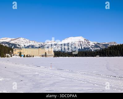 Winter Rocky Mountains - der gefrorene Lake Louise ist mit Schnee bedeckt, schneebedeckte Berge und Wälder, Fairmont Chateau am Ufer des gefrorenen Sees Stockfoto