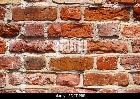 Alte rote Backsteinmauerstruktur mit natürlichen Mängeln und verwitterter Oberfläche. Rustikaler Backsteinhintergrund geeignet für Architektur, Konstruktion, Design p Stockfoto