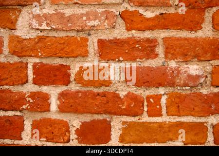 Alte rote Backsteinmauerstruktur mit natürlichen Mängeln und verwitterter Oberfläche. Rustikaler Backsteinhintergrund geeignet für Architektur, Konstruktion, Design p Stockfoto
