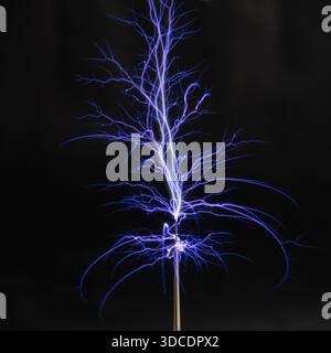 Elektrostatische Lichtbögen und Entladungen von einer Tesla-Spule mit blauem Leuchten in vollständiger Dunkelheit. Stockfoto