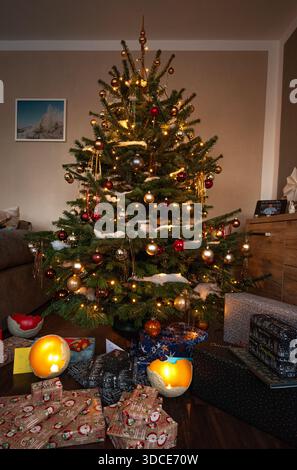 Wunderschön dekorierter Weihnachtsbaum mit warmen Lichtern, Ornamenten und gewickelten Geschenken in einem gemütlichen Wohnzimmer, der einen festlichen und fröhlichen Feiertag schafft Stockfoto
