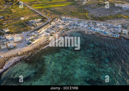 Aus der Vogelperspektive auf die felsige Küste trifft auf das klare türkisfarbene Wasser und zeigt das kleine Dorf, das zwischen Meer und Land eingebettet ist, L-Armier, Il- Stockfoto