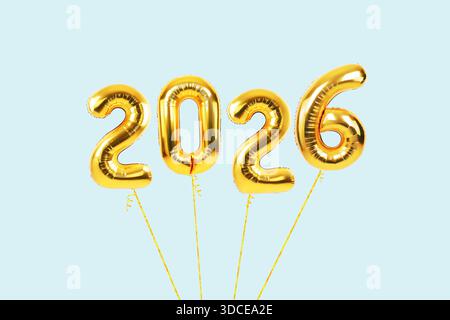 Goldene Folienballons, die die Zahl 2026 auf hellblauem Hintergrund beschreiben. Festliches, unterhaltsames und feierliches Konzept für Silvesterparty Stockfoto