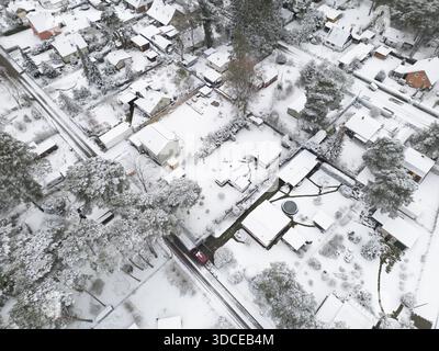 Blick aus der Vogelperspektive auf schneebedeckte Dächer und frostige Bäume, die eine ruhige Winterwunderlandszene schaffen, Bestensee, Brandenburg, Deutschland. Stockfoto