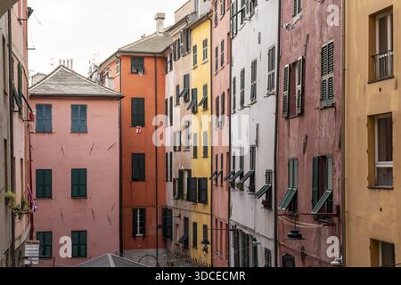 Blick auf lebendige Gebäude stehen Schulter an Schulter, ihre Fassaden sind ein Flickenteppich aus Pink, Orange, Gelb und weiß unter einem bedeckten Himmel, Genua, Ligur Stockfoto