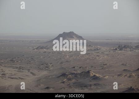 Die raue, trockene Landschaft entfaltet sich aus der Luft in gedämpften Erdtönen, unterbrochen von einem einsamen Berg, der aus den einsamen Ebenen aufsteigt, Reko Diq, Bal Stockfoto