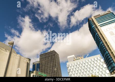 Madrid, Spanien - 09. November 2016: Blick auf die hoch aufragenden Wolkenkratzer, die den leuchtend blauen Himmel durchstechen, gespickt mit flauschigen weißen Wolken, die die Dynamik einfangen Stockfoto