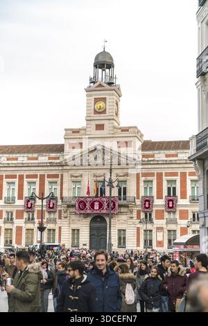 Madrid, Spanien - 09. November 2016: Blick auf die historische Casa de Correos, die in sanftem Licht getaucht ist und deren Uhrenturm über einer hektischen Menschenmenge in den Himmel ragt. Stockfoto