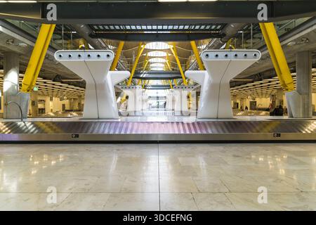 Madrid, Spanien - 09. November 2016: Blick auf die glänzenden, polierten Böden, die die hellen, weißen Gepäckausgabestrukturen unter dem modernen Gelb reflektieren Stockfoto