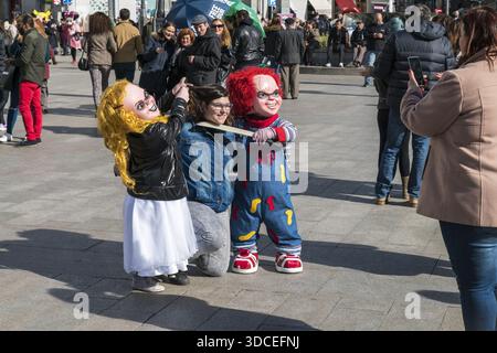 Madrid, Spanien - 9. November 2016: Blick auf zwei Frauen, die spielerisch eine Holzplanke hochhalten, während sie mit einer als Chucky gekleideten Person posieren. Stockfoto