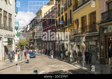 Madrid, Spanien - 09. November 2016: Blick auf eine belebte Straßenszene, in der Fußgänger an bunten Gebäuden vorbeischlendern, die in warmes Sonnenlicht getaucht sind, unter del Stockfoto